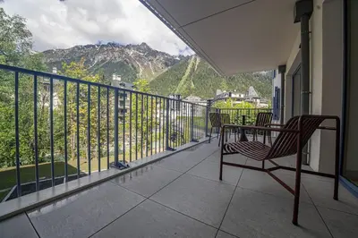 a balcony with a table and chairs and mountains at Paradisa Balcon du Géant Elegantly designed 4-bedroom apartment in Chamonix-Mont-Blanc