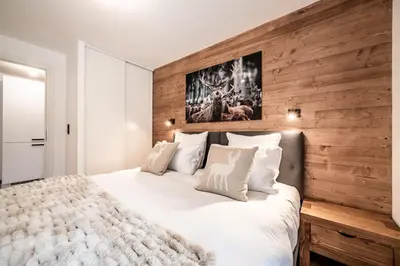 a bedroom with a large bed with a wooden wall at Apartment Alpinea, Les Houches - by EMERALD STAY in Les Houches