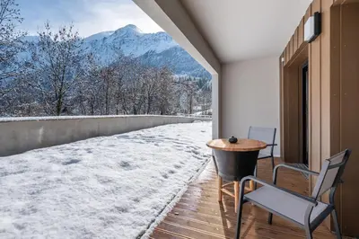 a table and chairs on a balcony with a view of a mountain at Apartment Alpinea, Les Houches - by EMERALD STAY in Les Houches