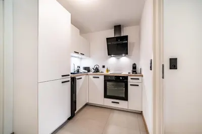 a kitchen with white cabinets and a refrigerator at Apartment Alpinea, Les Houches - by EMERALD STAY in Les Houches