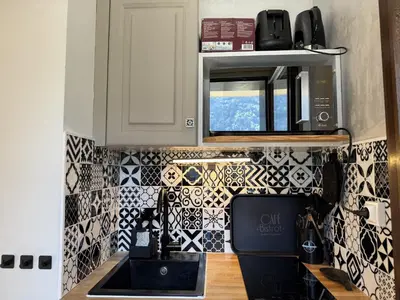 a kitchen with black and white tiles on the wall at La vue du Rosay - Balcon - Vues in Saint-Gervais-les-Bains