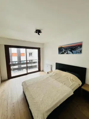 a bedroom with a bed and a large window at Balcons Alpins - Appartement rénové à St-Gervais in Saint-Gervais-les-Bains