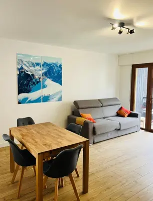 a living room with a table and a couch at Balcons Alpins - Appartement rénové à St-Gervais in Saint-Gervais-les-Bains