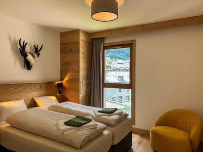 two beds in a room with a window and a chair at Le Yeti (4 Pers) in Chamonix-Mont-Blanc