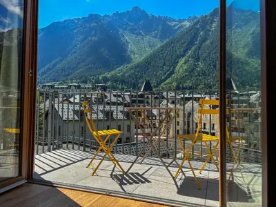 two chairs and a table on a balcony with mountains at Le Yeti (4 Pers) in Chamonix-Mont-Blanc