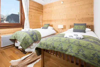 two beds in a room with wooden walls at Le Paradis 24 apartment - Chamonix All Year in Chamonix-Mont-Blanc
