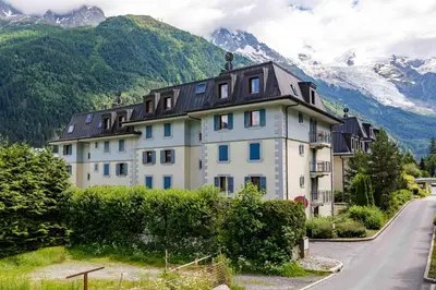 a large white house with mountains in the background at Le Paradis 27 apartment - Chamonix All Year in Chamonix-Mont-Blanc