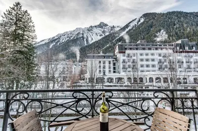 a table with a bottle of wine on a balcony with mountains at Le Paradis 27 apartment - Chamonix All Year in Chamonix-Mont-Blanc