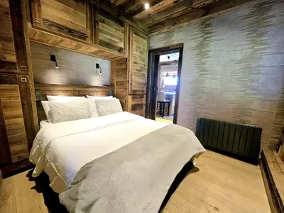 a bedroom with a large white bed with wooden walls at Cozy apartment in Mègeve center in Megève