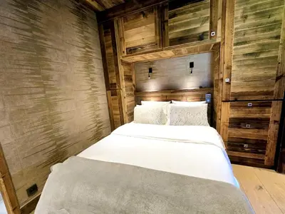 two beds in a room with wooden walls at Cozy apartment in Mègeve center in Megève