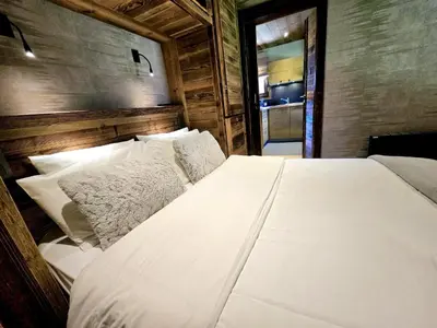 a bedroom with a white bed with a wooden wall at Cozy apartment in Mègeve center in Megève