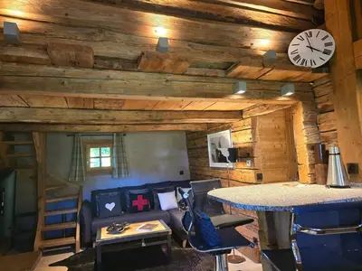 a living room with a couch and a clock on the wall at Le Mazot in Megève