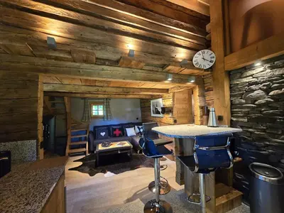 a living room with a stone wall and a table at Le Mazot in Megève