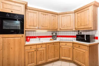a kitchen with wooden cabinets and black appliances at Le Paradis 18 - Chamonix All Year in Chamonix-Mont-Blanc
