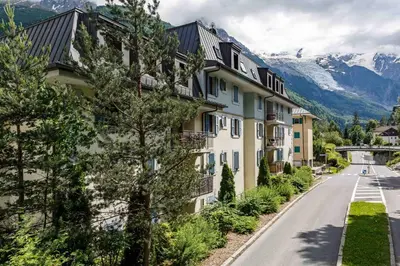 a building on a street with mountains in the background at Le Paradis 18 - Chamonix All Year in Chamonix-Mont-Blanc