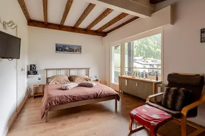 a bedroom with a bed and a chair and a window at Studio avec vue sur les montagnes in Les Contamines-Montjoie
