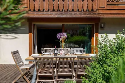 a wooden table with chairs and flowers on a patio at Chamois Apartment- Chamonix All Year in Chamonix-Mont-Blanc