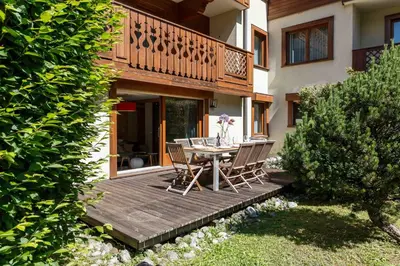 a wooden deck with a table and chairs on it at Chamois Apartment- Chamonix All Year in Chamonix-Mont-Blanc