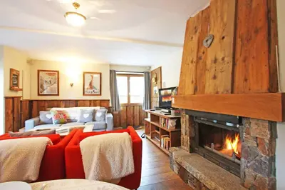 a living room with a red couch and a fireplace at La Ferme des Praz apartment - Chamonix All Year in Chamonix-Mont-Blanc