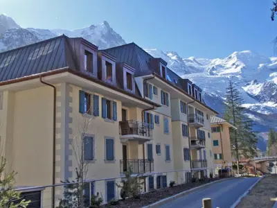 a building with snow capped mountains in the background at Le Paradis 18b - Chamonix All Year in Chamonix-Mont-Blanc