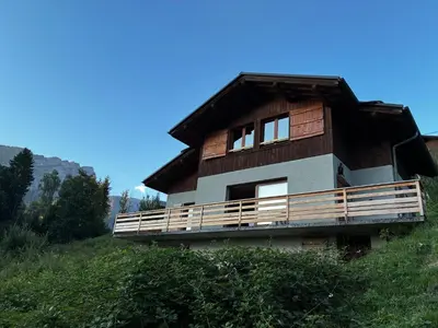 a wooden house with a balcony on a hill at Carpe Diem in Sixt