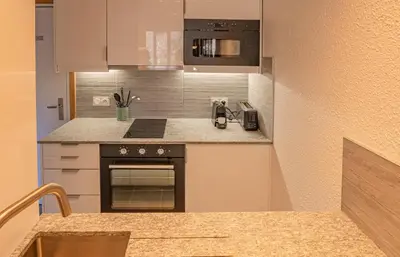 a small kitchen with a stove and a microwave at Apartment Jonquille 2C - Chamonix Peaks Getaway in Chamonix-Mont-Blanc