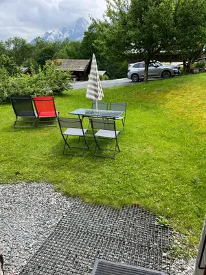 a picnic table with two chairs and a tree on the grass at Studio vallée de Chamonix in Les Houches
