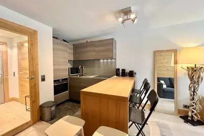 a kitchen with a wooden counter and chairs at Parenthèse Rochebrune in Megève