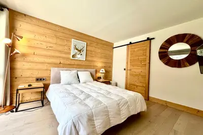 a bedroom with a bed and a wooden wall at Parenthèse Rochebrune in Megève