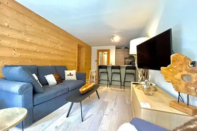 a living room with a blue couch and a tv at Parenthèse Rochebrune in Megève