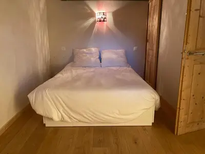 a bed with white sheets and pillows in a room at Grand appartement familial in Combloux