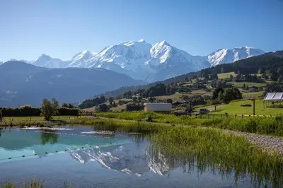 a river with snow capped mountains in the background at Grand appartement familial in Combloux