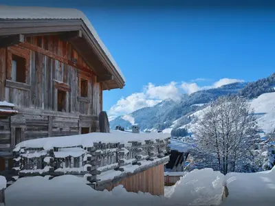 a wooden house covered in snow with mountains in the background at Chalet Snow Love - OVO Network in Megève