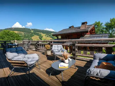 a deck with chairs and a table and a house at Chalet Snow Love - OVO Network in Megève