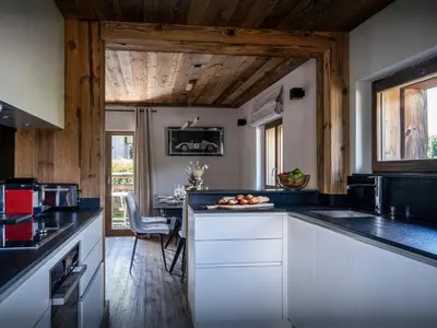 a kitchen with white cabinets and a counter with a table at Chalet Snow Love - OVO Network in Megève