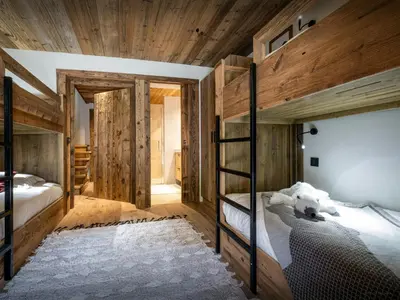 a bedroom with two bunk beds and wooden walls at Chalet Snow Love - OVO Network in Megève