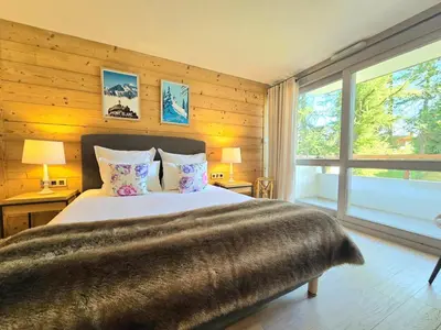 a bedroom with a large bed and a large window at Modern apartment Rochebrune ski in ski out in Megève
