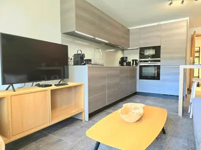 a kitchen with a large flat screen tv and a table at Modern apartment Rochebrune ski in ski out in Megève