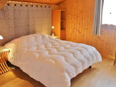 a large white bed in a wooden bedroom at Chalet spacieux à Samoëns, proche village, jusqu'à 11 personnes, WiFi, parking - FR-1-815-3 in Samoëns