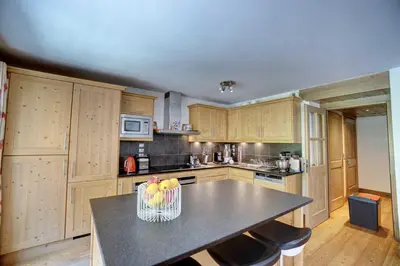 a kitchen with wooden cabinets and a basket of fruit at Hameaux du glaciers in Les Houches