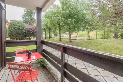 a porch with a red table and chairs on it at Studio Capucines - Welkeys in Megève