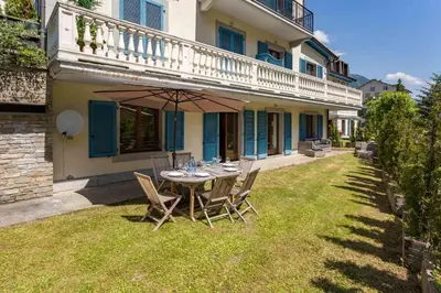 a table with an umbrella in the yard of a house at Pothecary apartment -Chamonix All Year in Chamonix-Mont-Blanc