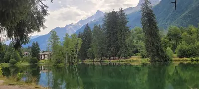 a lake with trees and mountains in the background at Grand studio près Lac Gaillands in Chamonix-Mont-Blanc