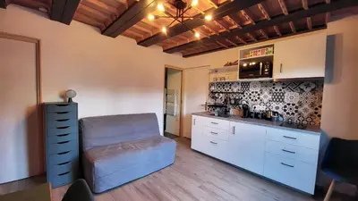 a kitchen with white cabinets and a chair in it at Studio 181 in Combloux