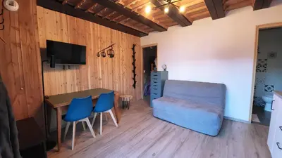 a living room with a table and blue chairs at Studio 181 in Combloux