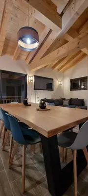 a dining room with a wooden table and blue chairs at Appart 3 pièces Cosy - idéal famille & sports Le Cairn De Samoëns in Samoëns