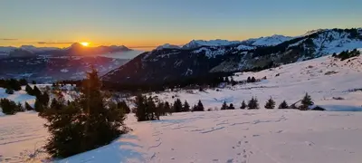 a snow covered mountain with the sun setting in the distance at Appart 3 pièces Cosy - idéal famille & sports Le Cairn De Samoëns in Samoëns