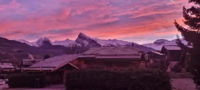 a house in front of a sunset with mountains at Appart 3 pièces Cosy - idéal famille & sports Le Cairn De Samoëns in Samoëns