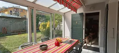 a table on a porch with a dog looking out the window at Maison idéalement située toutes mobilités in Saint-Gervais-les-Bains