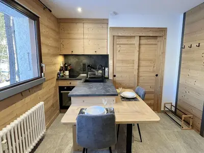a kitchen with wooden cabinets and a wooden table with chairs at Appartement Studio, 2 couchages, MEGEVE MEG400-T122 in Megève